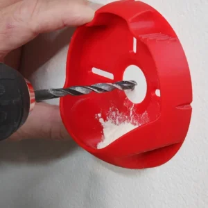 Recolector rojo de polvo para taladro colocado sobre una pared durante una perforación