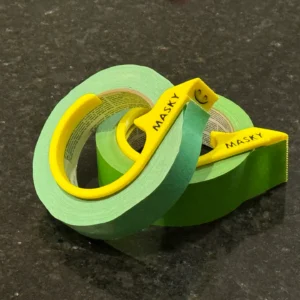 Cortadores amarillos impresos en 3D colocados sobre rollos de cinta de enmascarar verde