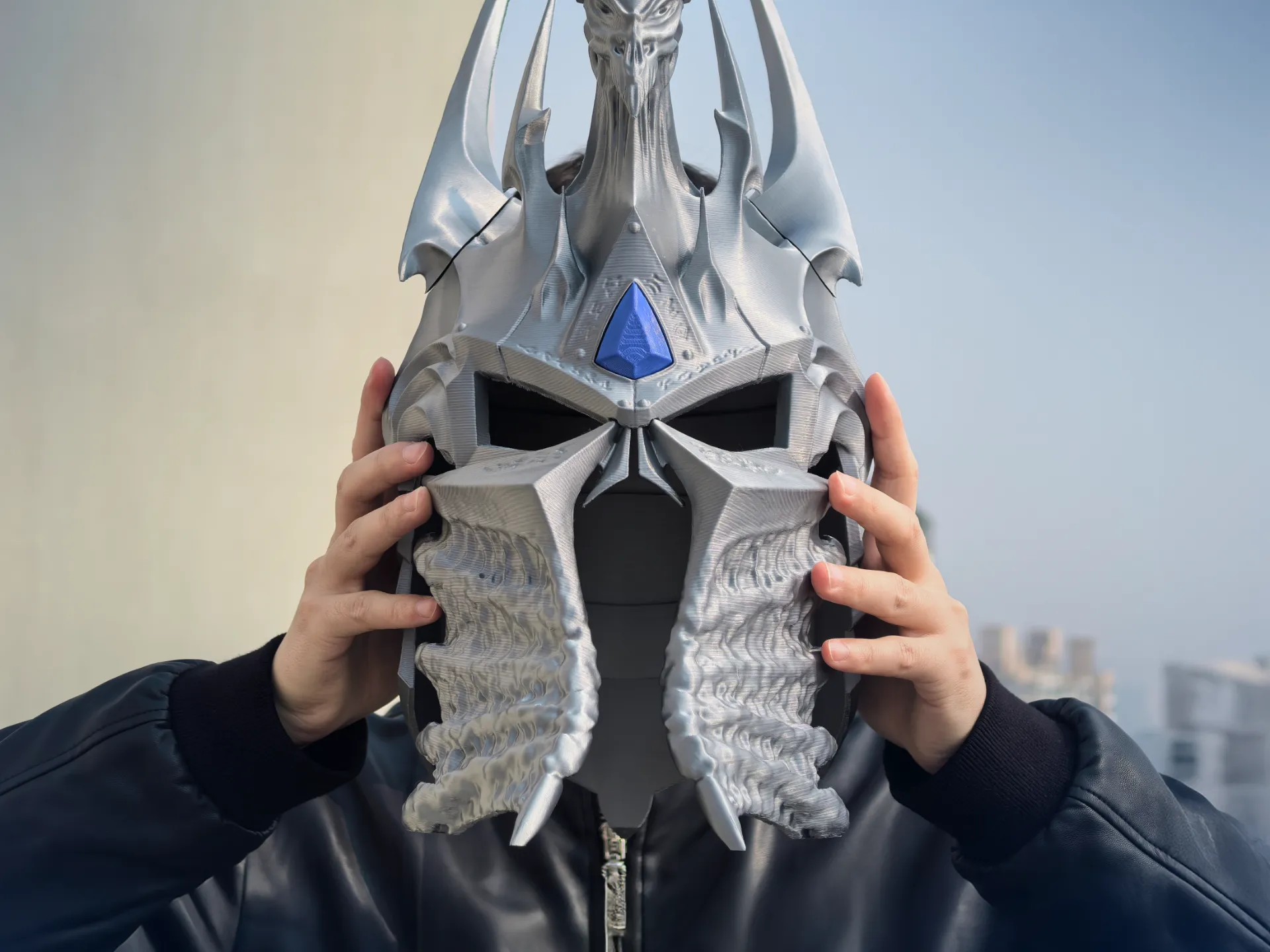 Casco de fantasía oscura impreso en 3D con diseño inspirado en un rey helado, en color plata con detalle azul frontal