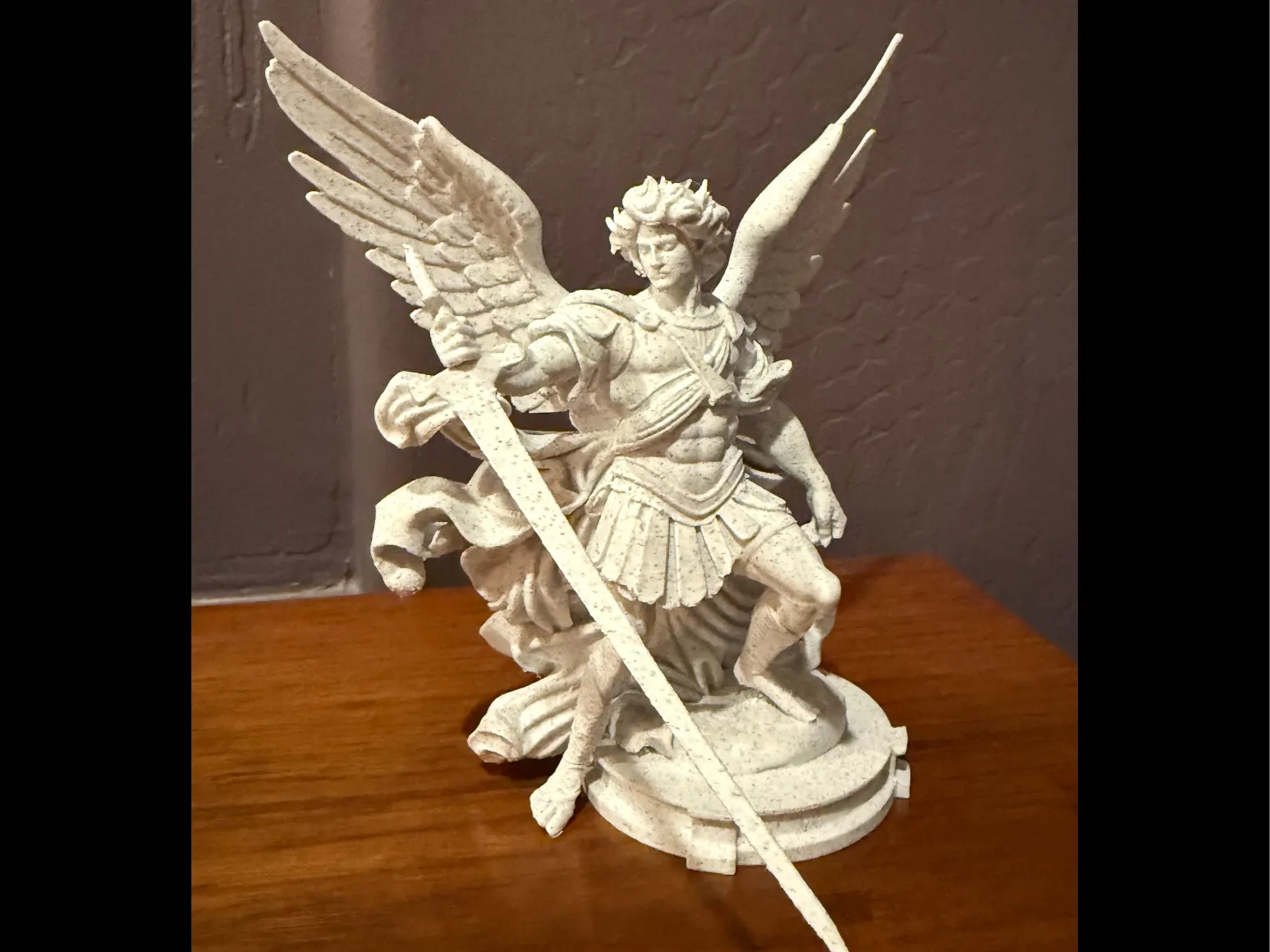 Figura de San Miguel Arcángel impresa en 3D con alas, armadura y espada sobre base decorativa
