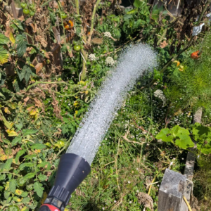 Boquilla negra para riego con manguera impresa en 3D distribuyendo agua sobre plantas de jardín