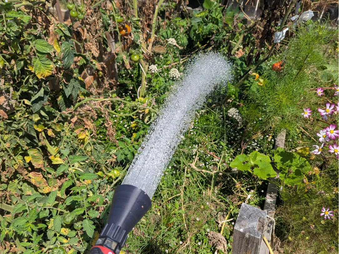 Boquilla negra para riego con manguera impresa en 3D distribuyendo agua sobre plantas de jardín